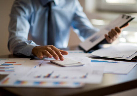 Business accounting concept, Business man using calculator with computer laptop, budget and loan paper in office.