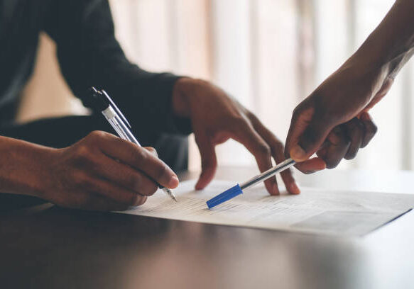 Cropped shot of an unrecognizable man filling a document with the help of a financial advisor at home